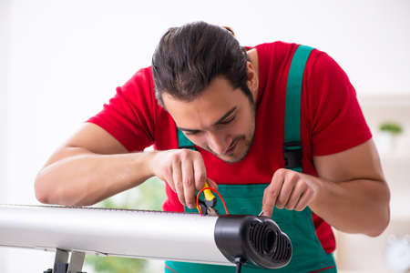 Young male contractor repairing heater indoorsの写真素材