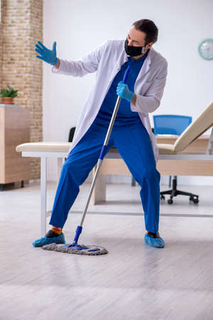 Young male contractor disinfecting clinic in pandemic conceptの写真素材