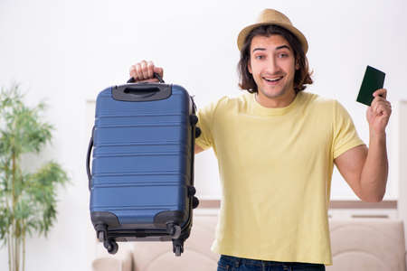 Young man holding passport and suitcase preparing for tripの写真素材