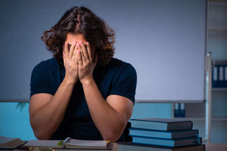 Young male student in the classroom at nightの写真素材