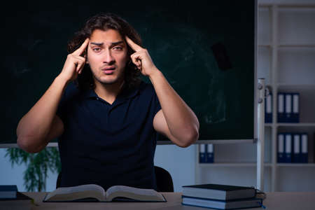 Young male student in the classroom at nightの写真素材