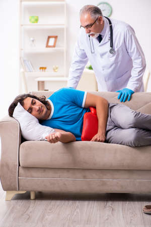 Two doctors visiting sick young man at homeの写真素材