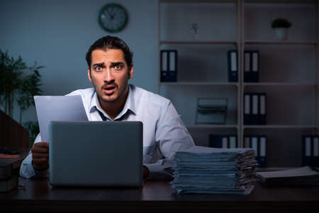 Young male employee working in the office night timeの写真素材