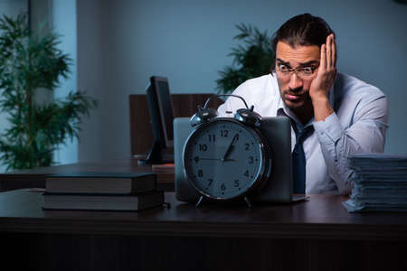Young male employee working in the office night timeの写真素材