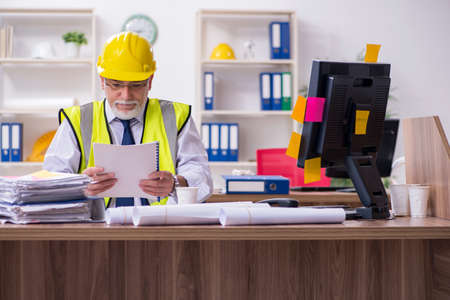 Old male architect working in the office