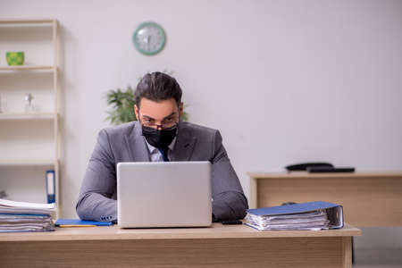 Young male employee in the office during pandemic diseaseの写真素材