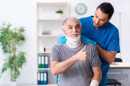 Young male doctor and old patient in first aid conceptの写真素材