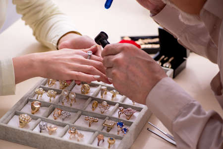 Young woman visiting old male jeweler