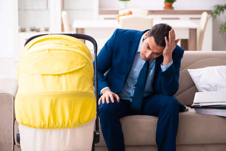 Young businessman looking after newborn at homeの写真素材