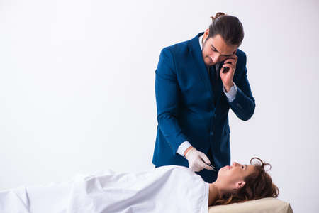 Police coroner examining dead body corpse in morgue