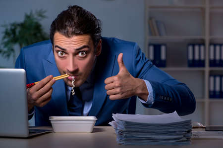 Hungry employee working late in the officeの写真素材