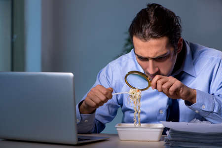 Hungry employee working late in the officeの写真素材