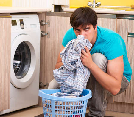 Young husband man doing laundry at homeの写真素材