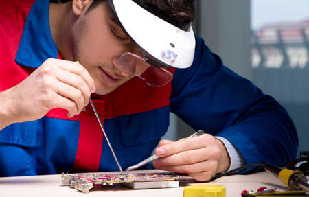 Computer specialist repairing PC late at nightの写真素材