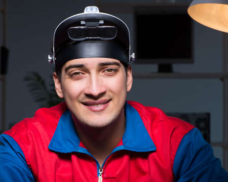 Computer specialist repairing PC late at nightの写真素材