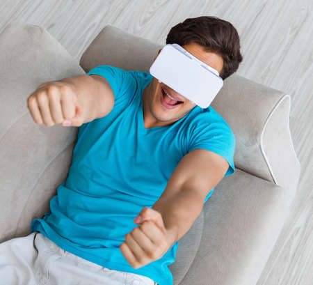 Young man wearing VR glasses relaxing on couch sofa
