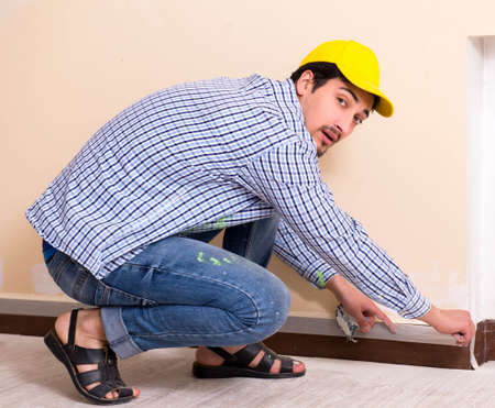 Young contractor sanding wall down with sandpaperの写真素材