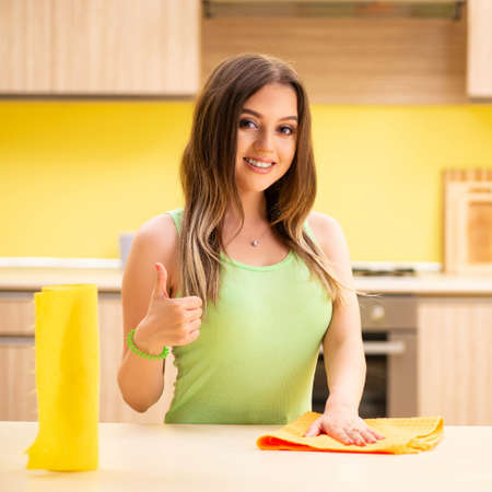Young beatifull woman polishing table in the kitchen