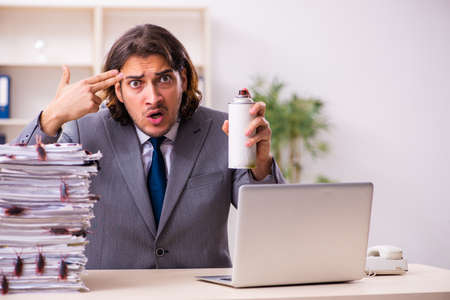 Young male employee and too many cockroaches in the officeの写真素材