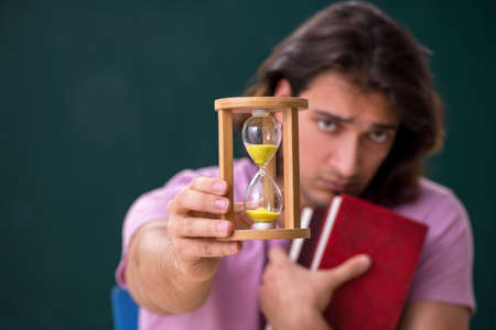 Young male student in the classroom at time management concept