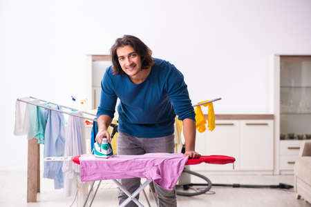 Young man husband doing clothing ironing at homeの写真素材