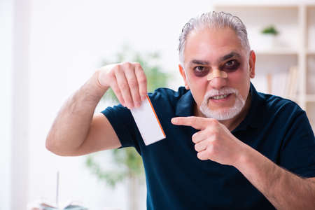 Old injured man in budget planning conceptの写真素材