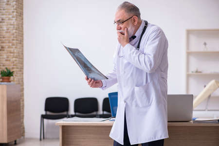 Old male doctor working in the clinic