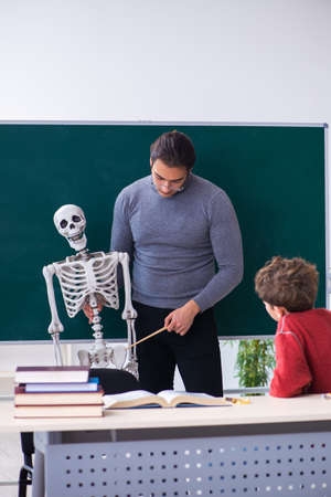 Young male teacher and schoolboy in the classroomの写真素材