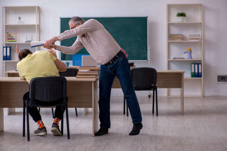 Old teacher and young male student in the classroomの写真素材