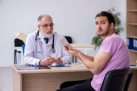 Young male patient visiting old male doctorの写真素材