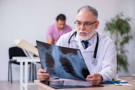 Old doctor radiologist examining young male patient
