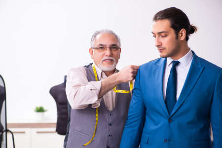 Young businessman visiting old male tailorの写真素材