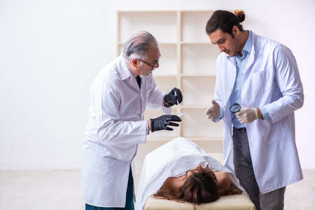 Police coroner examining dead body corpse in morgue