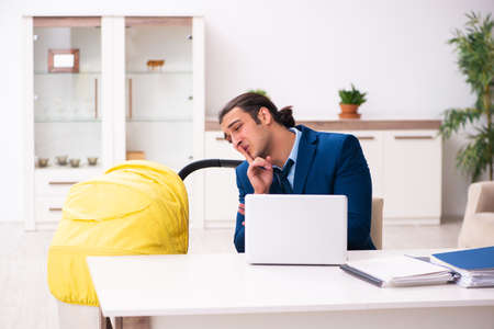 Young businessman looking after newborn at homeの写真素材