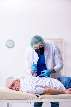 Old man visiting young male intern doctorの写真素材