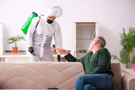 Young male sanitizer and old man indoorsの写真素材