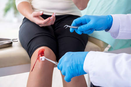 Leg injured woman visiting male doctorの写真素材