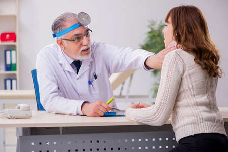 Young woman visiting old male doctor otorhinolaryngologistの写真素材