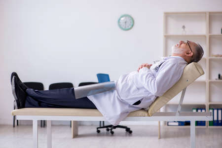 Old male doctor working in the clinicの写真素材