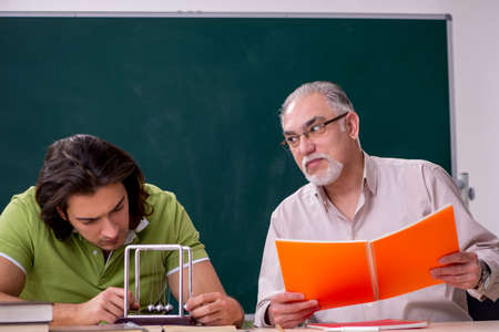 Old professor physicist and young student in the classroom