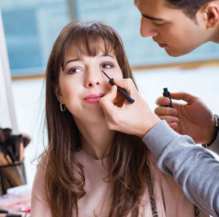 Man doing make-up for cute woman in beauty salonの写真素材