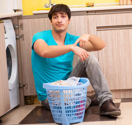 Young husband man doing laundry at homeの写真素材