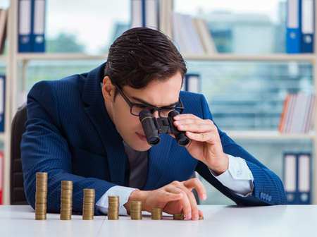 Businessman with stacks of coins in the officeの写真素材