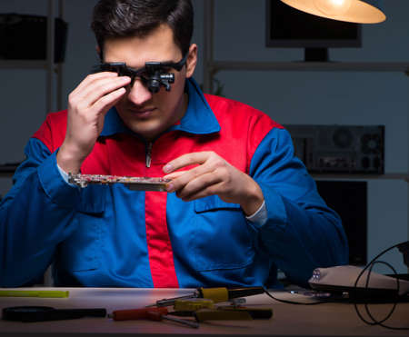 Computer specialist repairing PC late at night