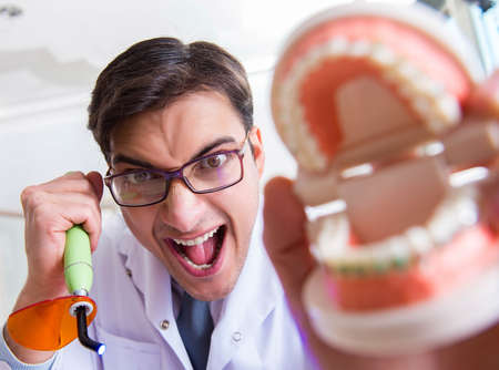 Funny dentist with curing light in medical conceptの写真素材