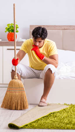 Young handsome man cleaning in the bedroomの写真素材