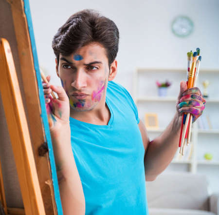 Young funny artist working on new painting in his studioの写真素材
