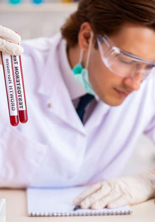 Young handsome lab assistant testing blood samples in hospitalの写真素材