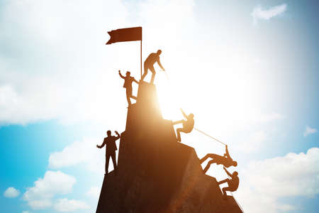 Concept of teamwork with team climbing mountain top