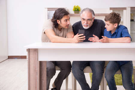 Grandfather learning new technology from son and grandsonの写真素材